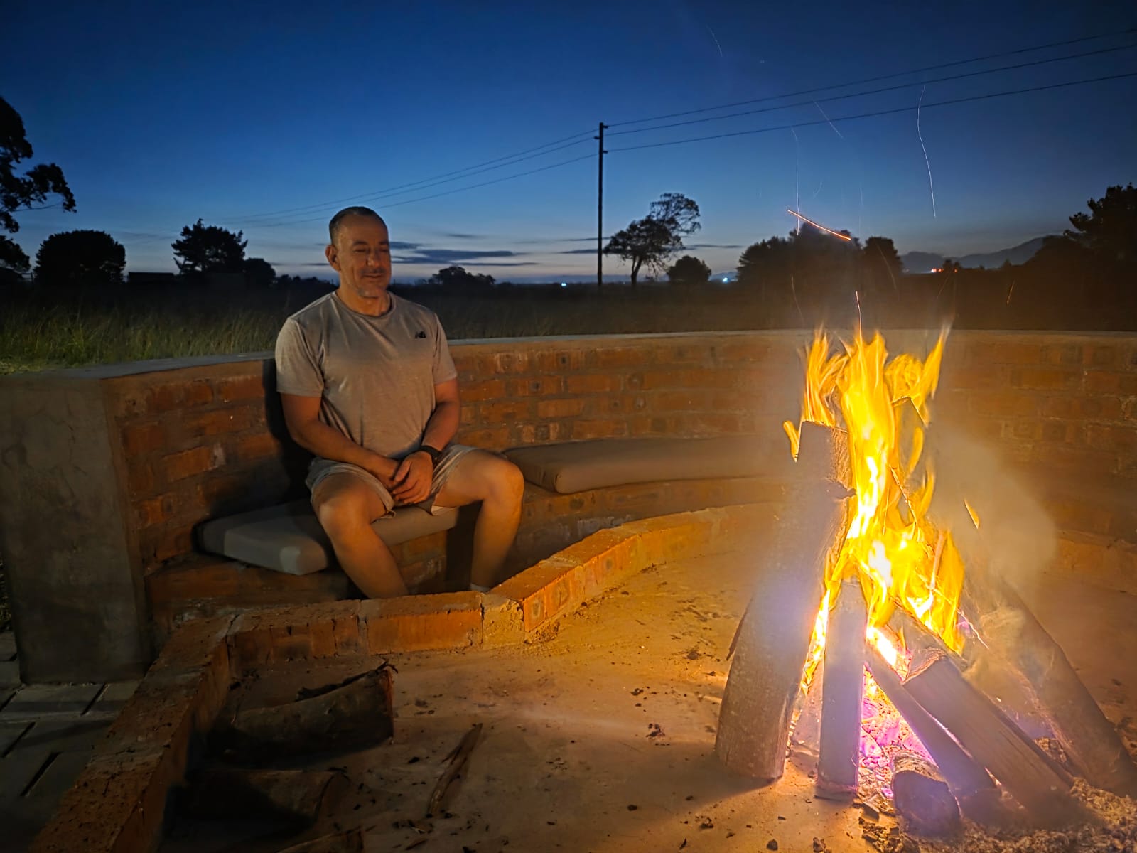 Evening fire at the Plaasrus braai pit — mountains fading to dusk behind